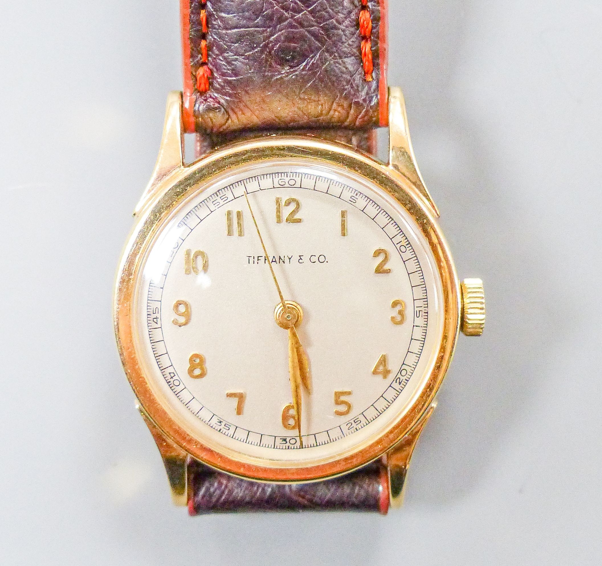 A lady's 14k Tiffany & Co manual wind wrist watch, on associated leather strap, case diameter 27mm, gross weight 28.8 grams.